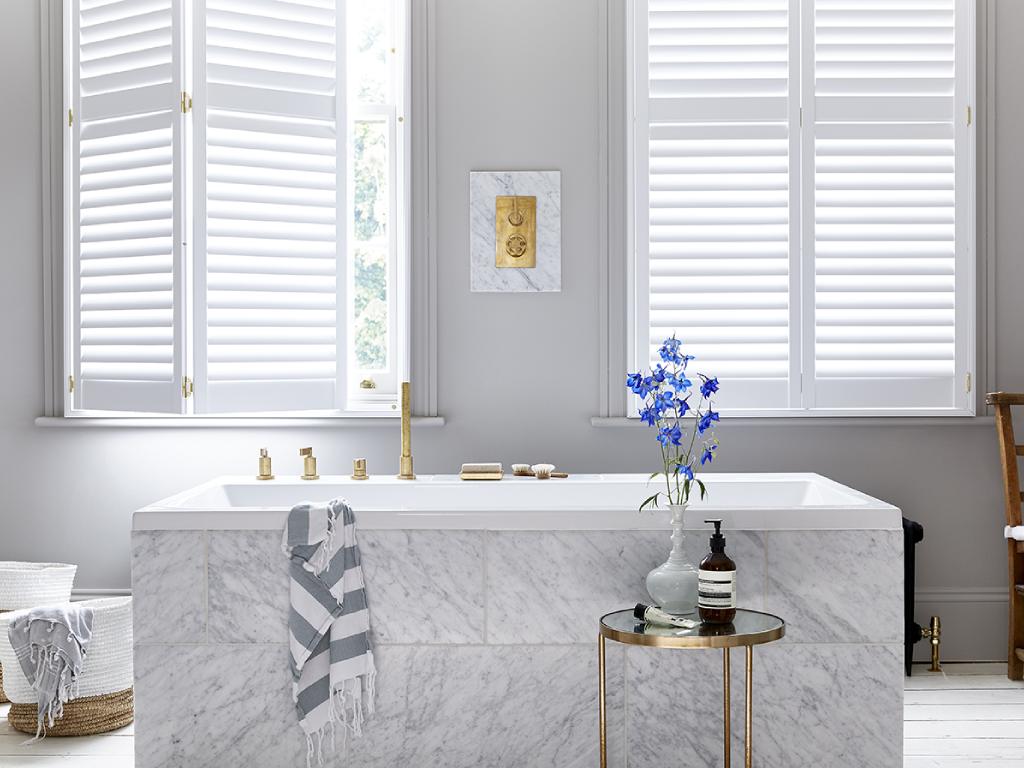 Elegant bathroom with white plantation shutters on the windows.