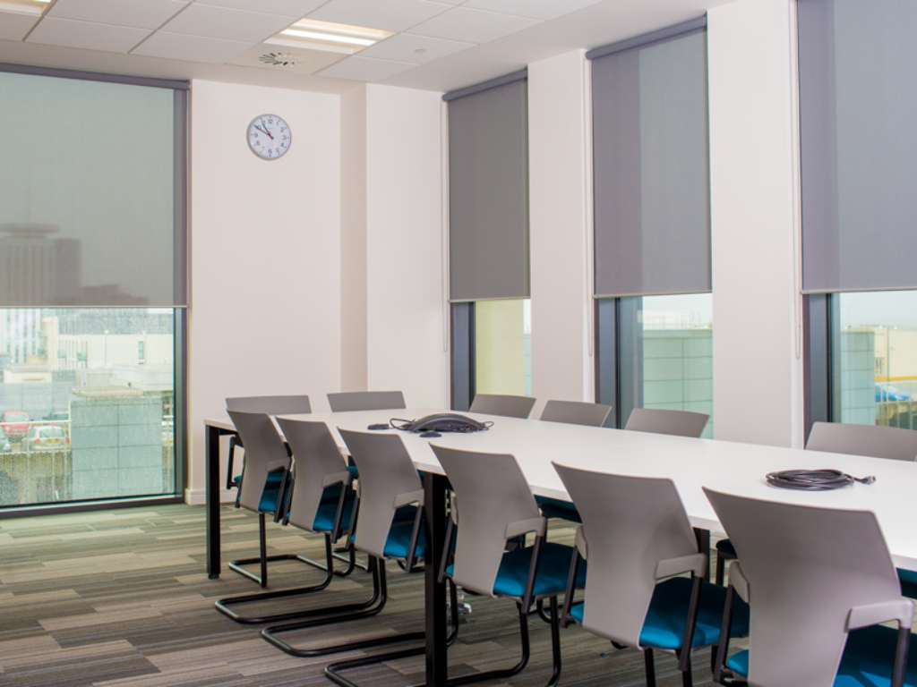 Modern office with gray roller shades on large windows.