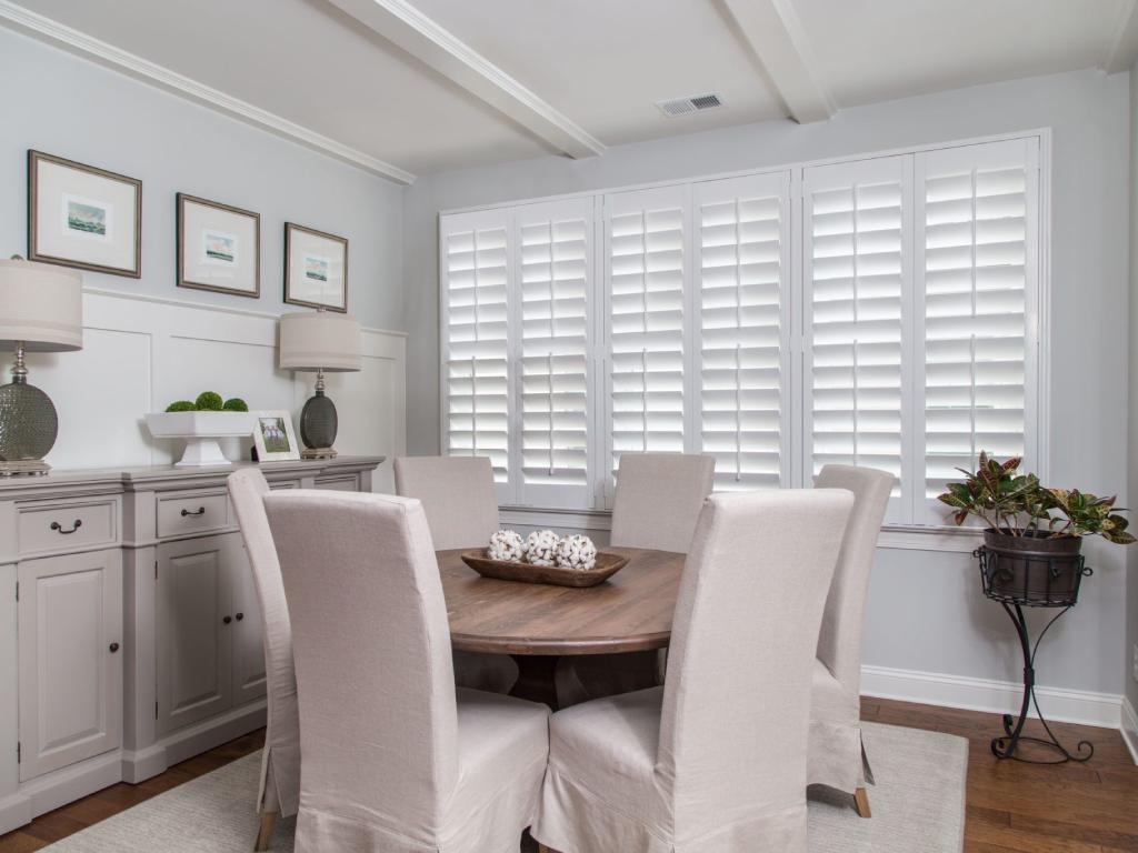 Modern dining room with white plantation shutters on windows.