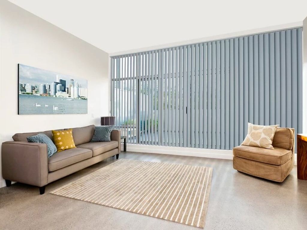 Living room with light blue vertical blinds covering a large window.