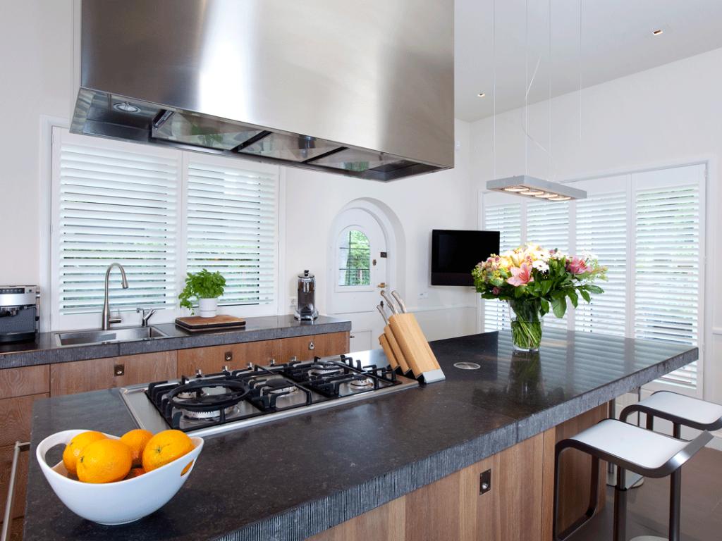 Modern kitchen with white plantation shutters covering the windows.