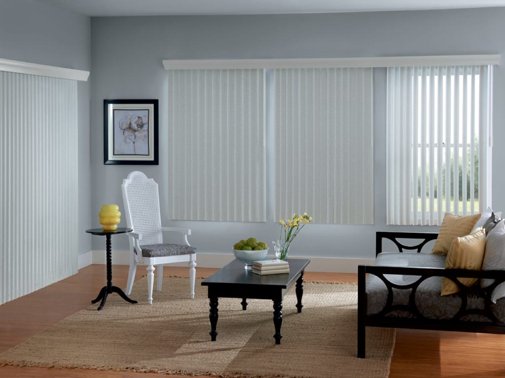 Modern living room with white vertical blinds covering large windows.