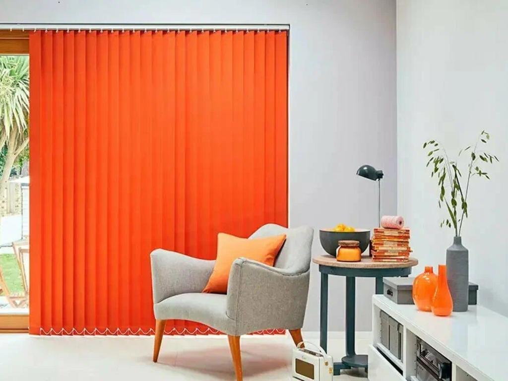 Living room with vibrant orange vertical blinds covering a sliding glass door.