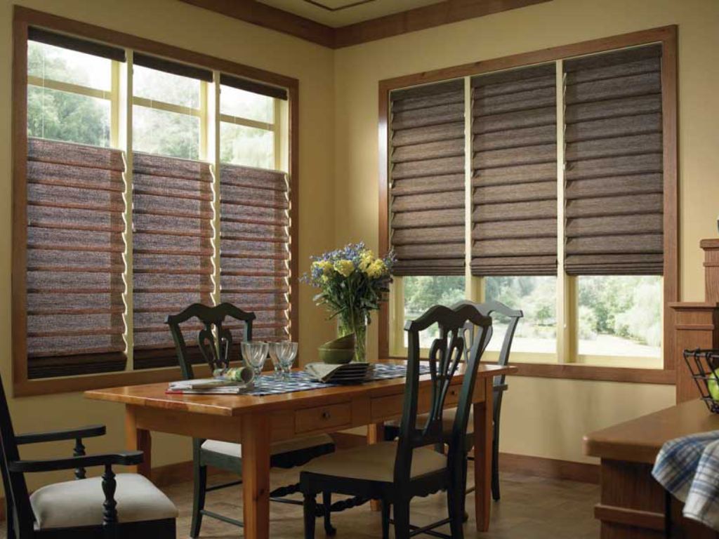 Dining room with brown Roman shades covering the windows.